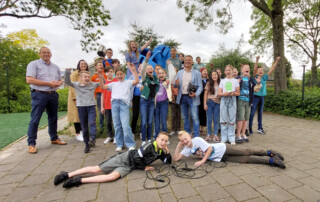 Groepsfoto van groep 8 van CBS De Schelp in Puttershoek bij de aftrap van de E-waste Race 2023. Ook op de foto directeur Huisman van de RAD en wethouder Robin Heij van gemeente Hoeksche Waard.