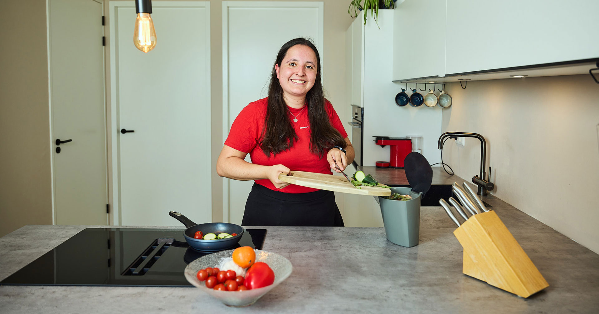 vrouw staat in een keuken en doet snijafval in het biobakje